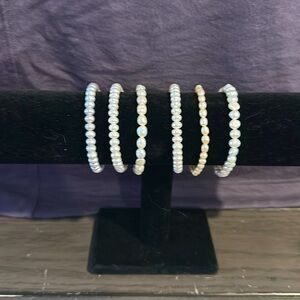 Set of six bead bracelets . Four are white , one light pink , one light grey